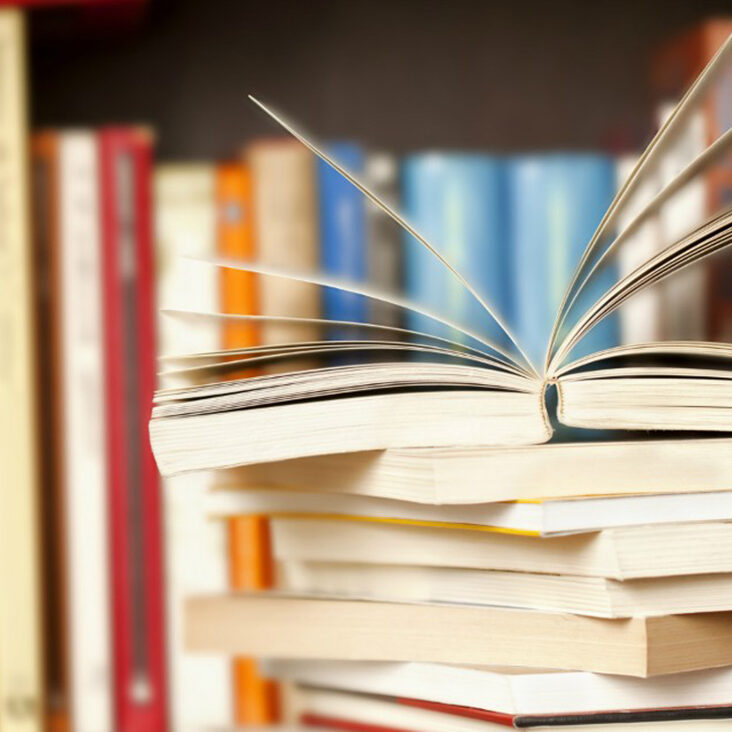 Open book sitting on top of stack of books in a library